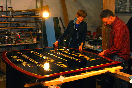 Kevin and Sandra Freeman are putting the finishing touches on a steel band around a large carved sign